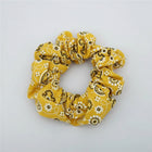 Yellow scrunchie with black and white pattern on a white surface